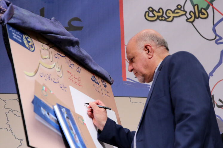 بیژن زنگنه، وزیر نفت در حال نوشتن یادداشت روی پوستر اطلس اکتشافات میدان‌های نفت و گاز ایران